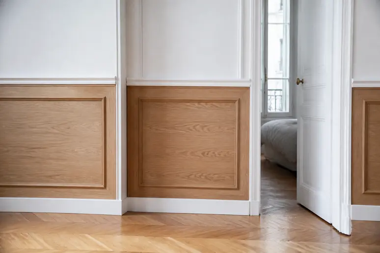Un soubassement mouluré de 90 cm, combinant lambris et plinthe, apporte une touche classique et chaleureuse à un intérieur parisien.