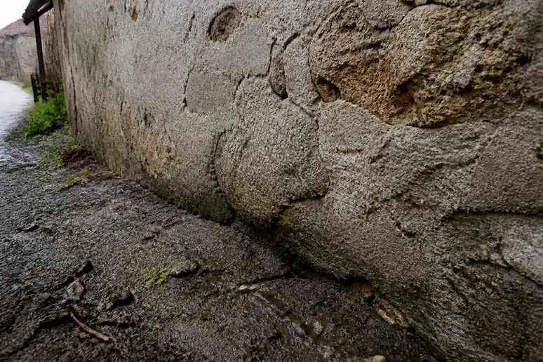 Fondations d'un mur de pierre ancien, en contact direct avec le sol humide, illustrant l'absence de barrière d'étanchéité adéquate.