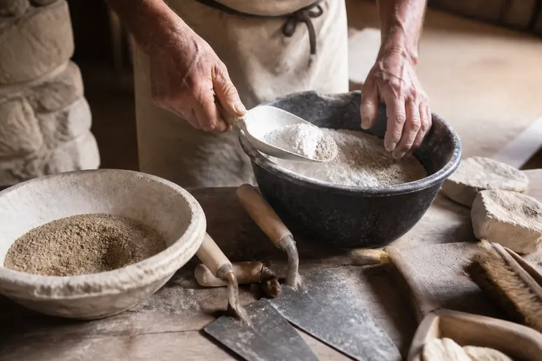 Mains expertes d'un maçon mélangeant chaux et sable pour un mortier de jointoiement traditionnel.