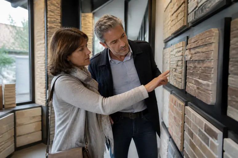Couple français choisissant des plaquettes de parement en pierre et brique pour un projet de rénovation intérieure.