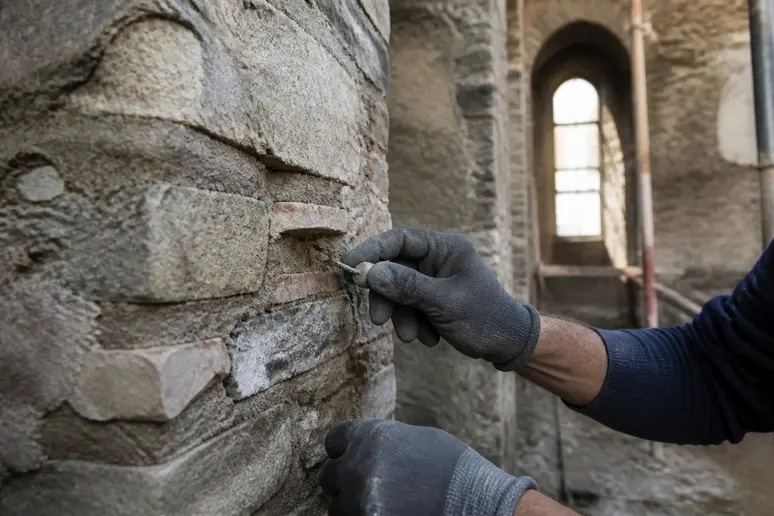 Ouvrier du bâtiment consolidant les murs en pierre ancienne lors de la renovation du batiment