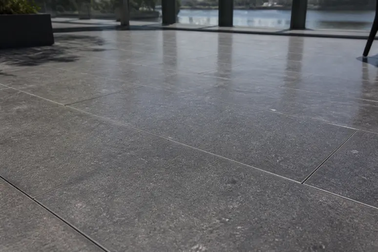 Dalle grise de terrasse anthracite exposée aux rayons du soleil estival en extérieur