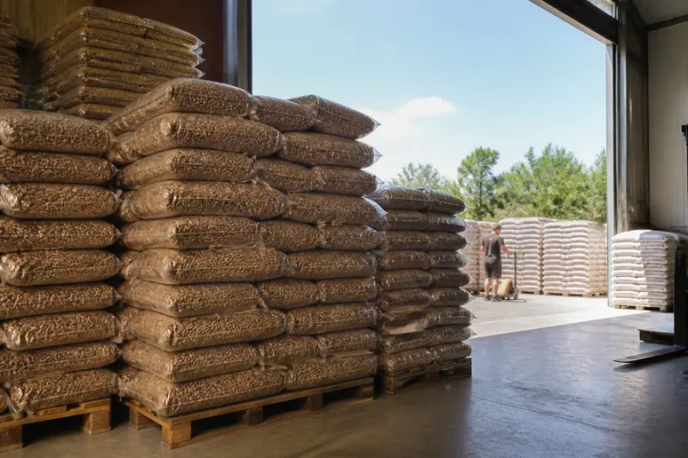 Piles de sacs de granulés disposées sur des palettes dans un dépôt de stockage.