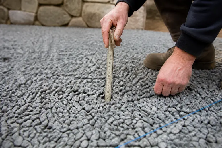 Mesure de l'épaisseur d'une couche de gravier pour une allée avec un mètre