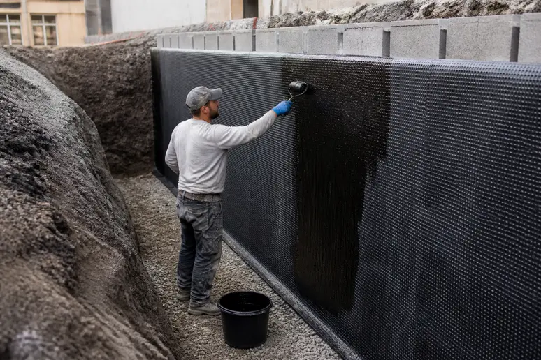 Pose d'une membrane d'étanchéité et d'un revêtement drainant sur un mur de soutènement de terrasse encaissée