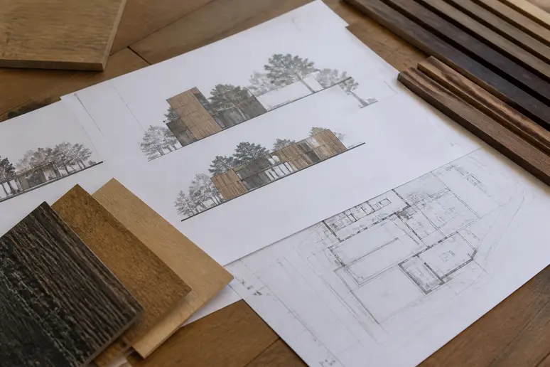 Plans d'architecte et échantillons de bardage bois posés sur une table pour préparer un dossier d'urbanisme