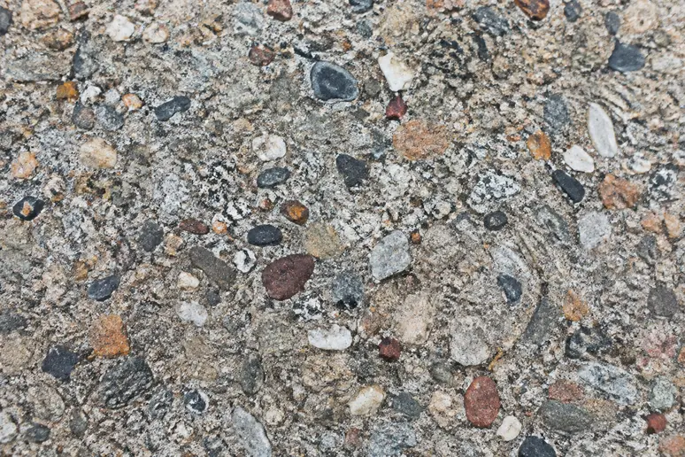 Gros plan sur une dalle en béton lavé montrant les granulats apparents en surface