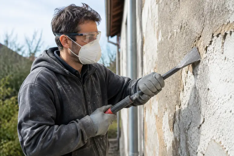 Artisan équipé de protections individuelles pour préparer son chantier de rénovation de façade.