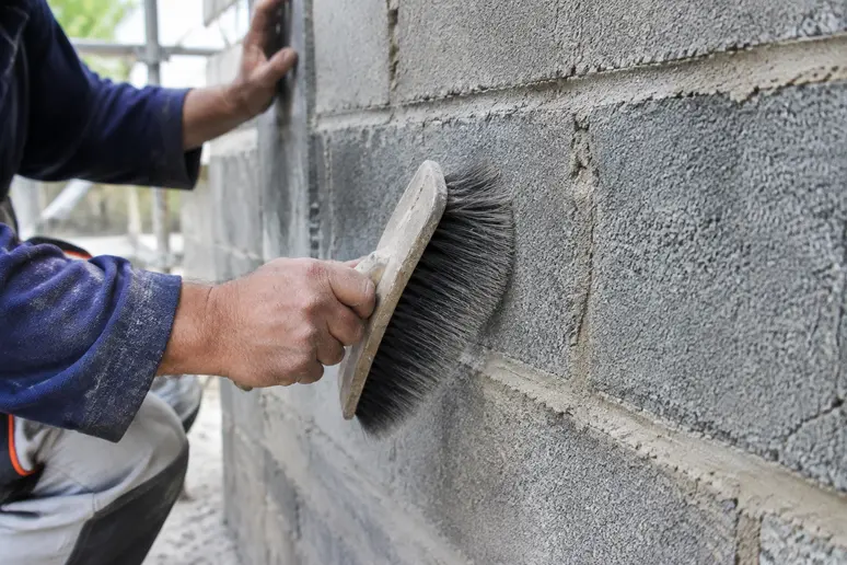 Nettoyage minutieux d'un mur extérieur en parpaing avant l'application de l'enduit de façade