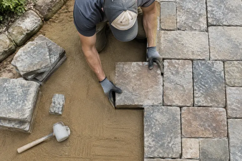 Pose d'un kit de pavés rustiques sur une terrasse extérieure en cours d'aménagement.