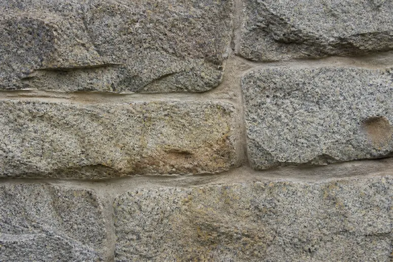 Détail des joints et de l'état de surface d'un mur en pierre de taille en granit.