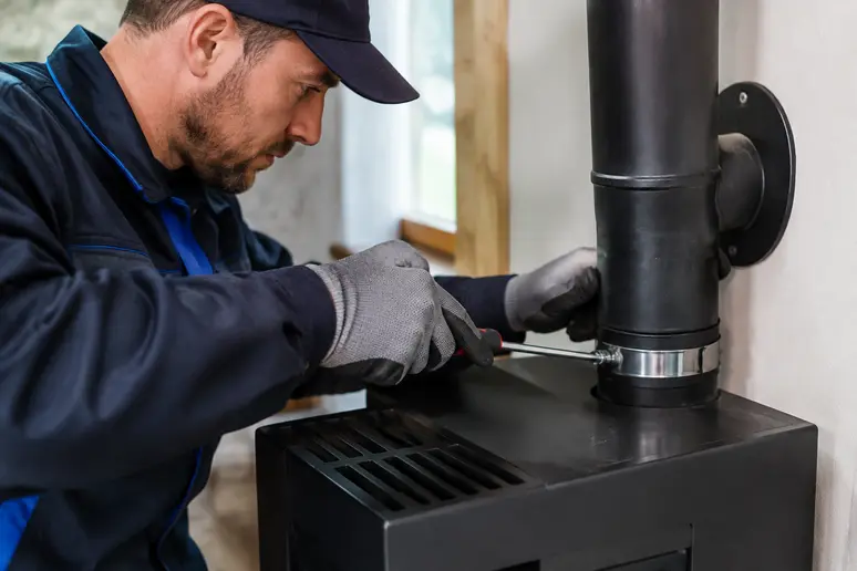 Artisan certifié effectuant le raccordement technique d'un poêle à granulés lors de la pose