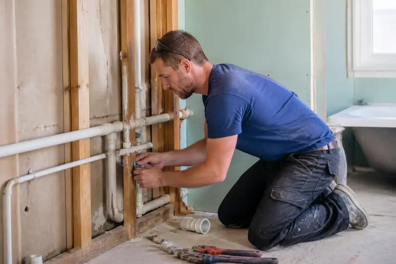 Plombier qualifié installant les réseaux d'eau lors de la rénovation d'une salle de bain à Cholet