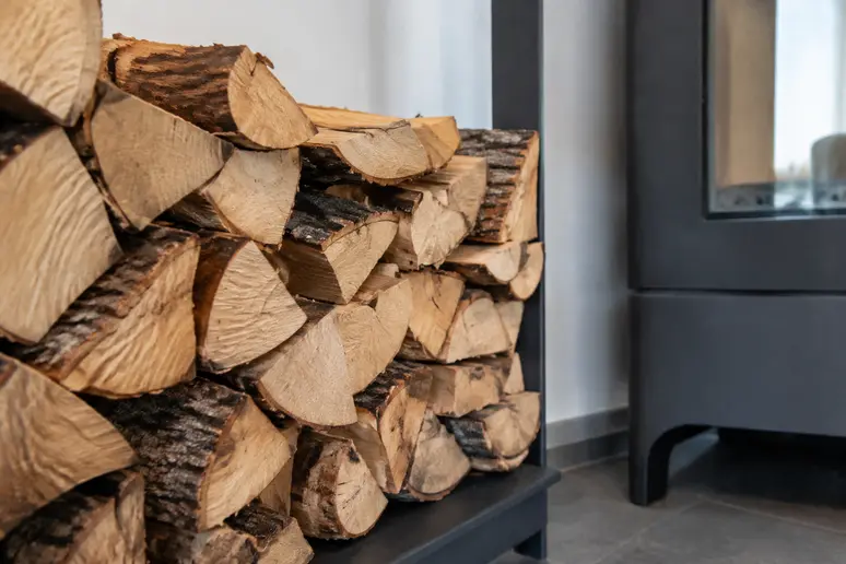 Bûches de bois de chauffage soigneusement stockées à proximité d'un poêle.