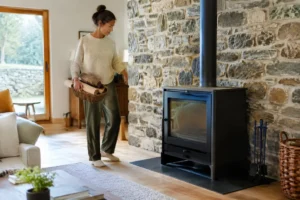 Un salon rénové avec un poêle à bois charnwood élégant adossé à un mur en pierre naturelle.