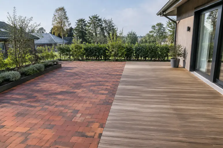 Aménagement d'une terrasse extérieure associant des pavés en brique rouge et des lames de bois.