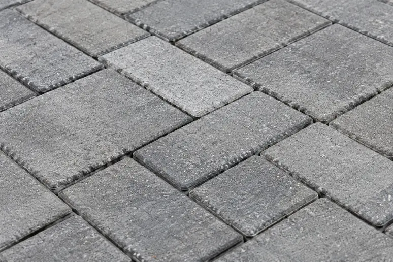 Pavage en blocs de béton texturés posés sur une terrasse extérieure bien aménagée